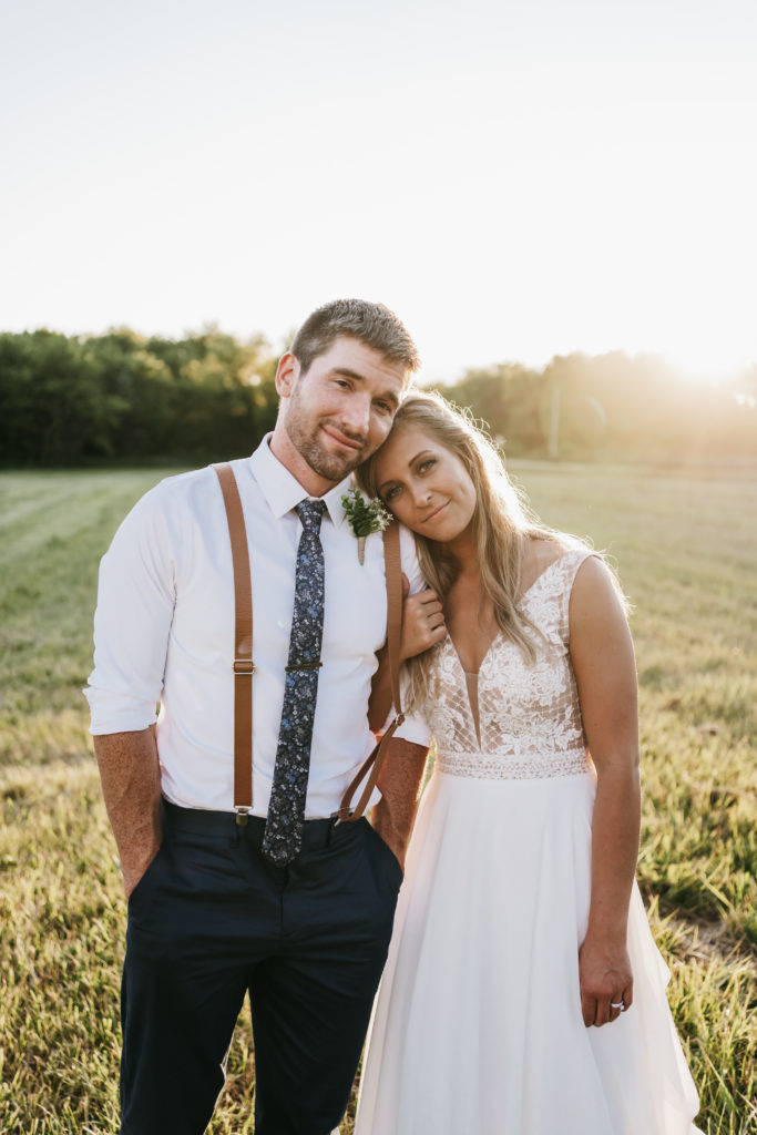Bride and Groom stand next to each other in open field