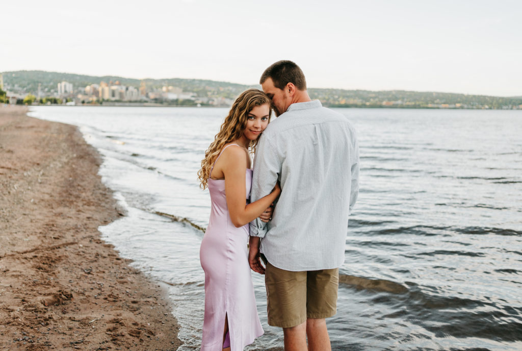 An engaged couple embraces on a beach in Duluth, Minnesota.