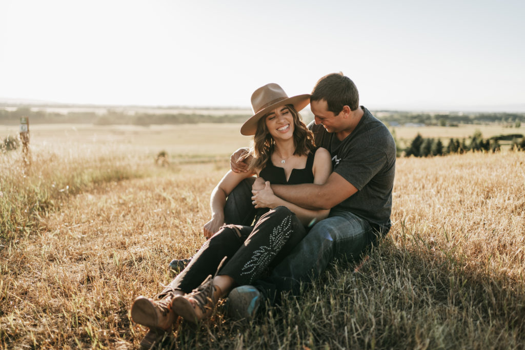 a couple sitting in a field and hugging on a mountain top in Bozeman, Montana.