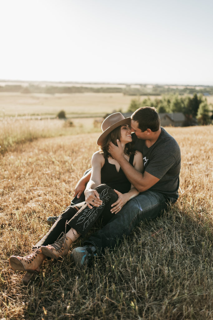a couple sitting in a field and hugging on a mountain top in Bozeman, Montana.