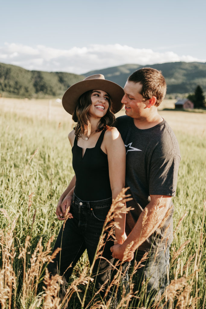An engaged couple holding hands in a field in Bozeman, Montana.