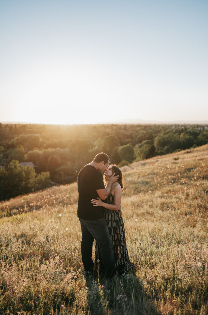 An engaged couple kissing at sunset on a mountain in Bozeman, Montana.