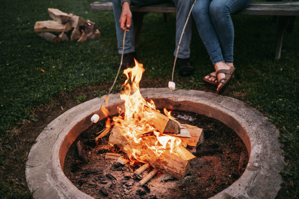 An engaged couple roasts marshmallows by a campfire.
