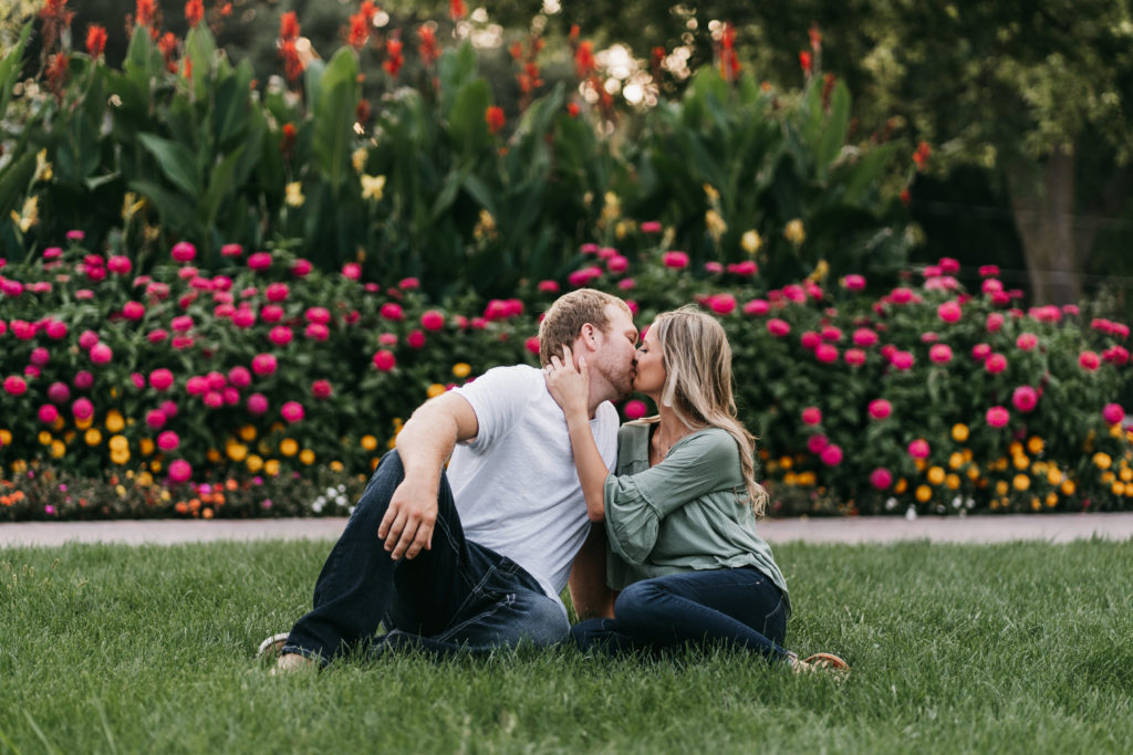 A couple kisses in front of flowers in a park in the spring