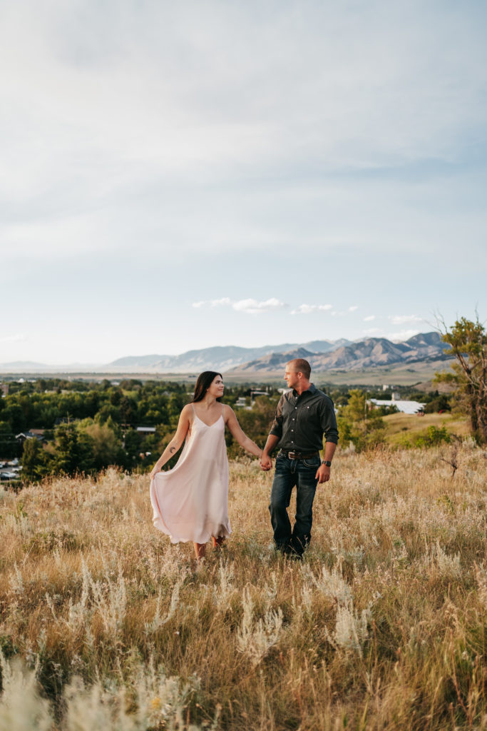A couple holds hands on a mountaintop in Bozeman, Montana.