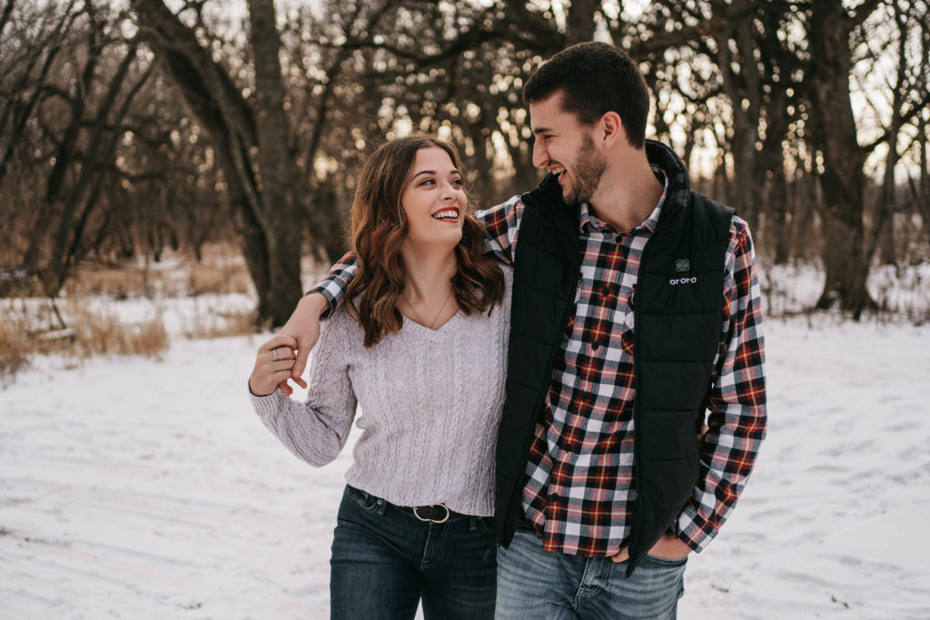 A couple laughs while walking toward the camera in the winter.