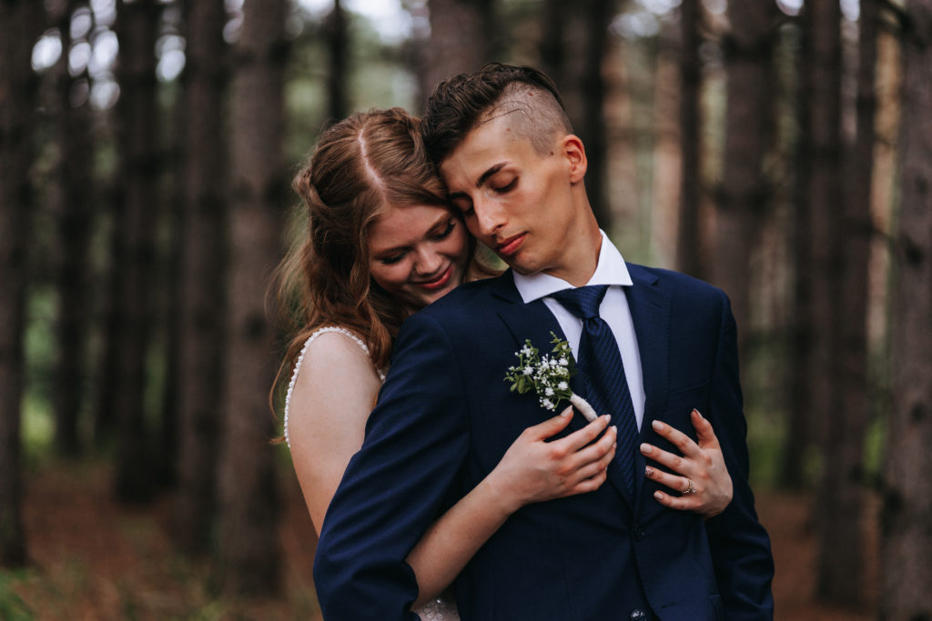 Bride and groom hug in the forest during their backyard wedding in Northern Minnesota
