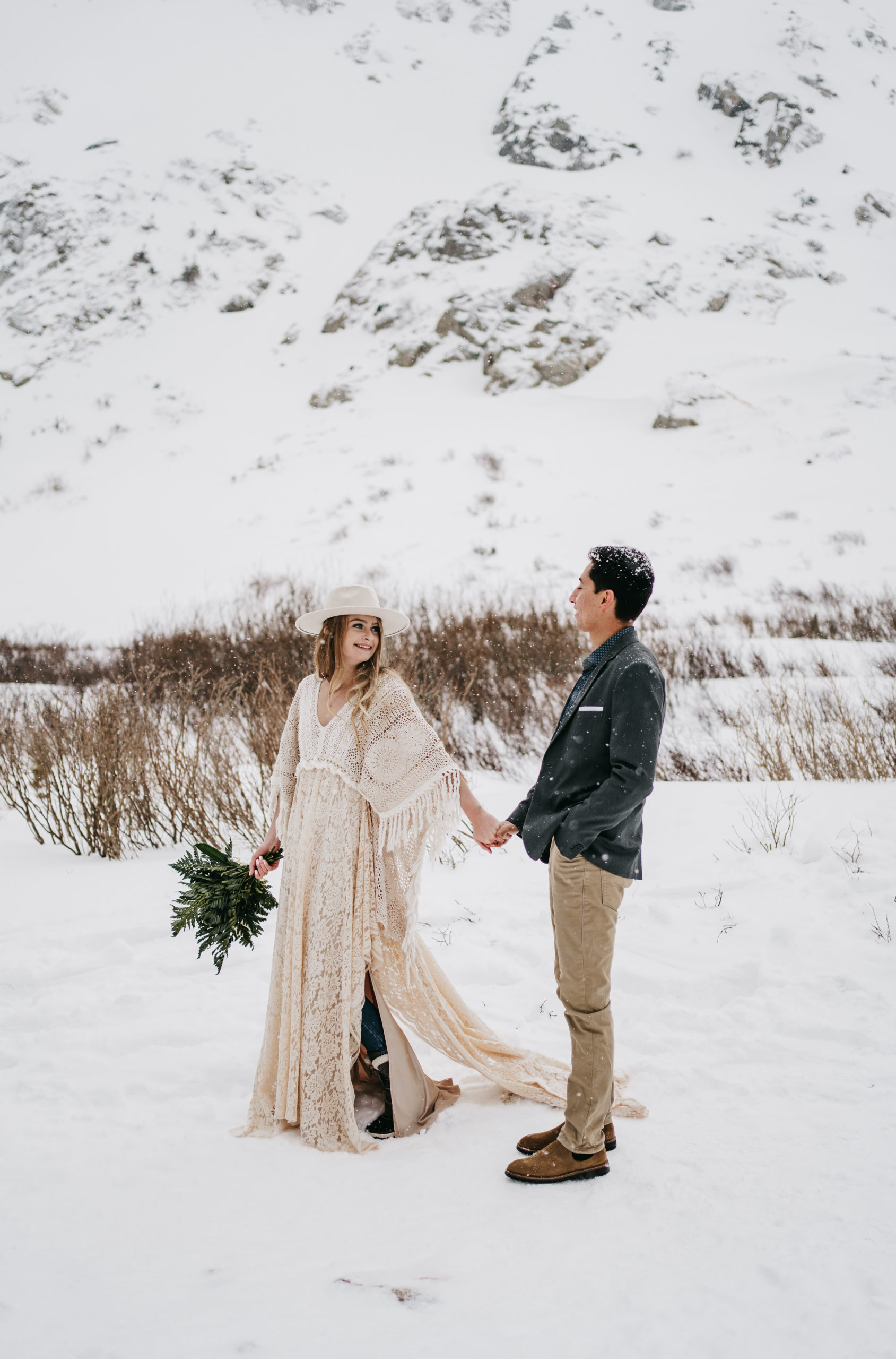 An eloping couple walking through snow in front of a glacier in the Colorado Rocky Mountains