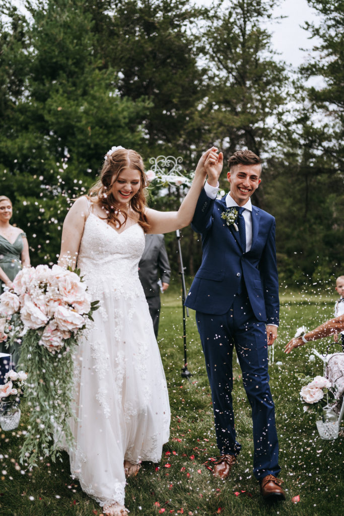 Bride and groom smile as they exit their ceremony in Northern Minnesota during confetti exit