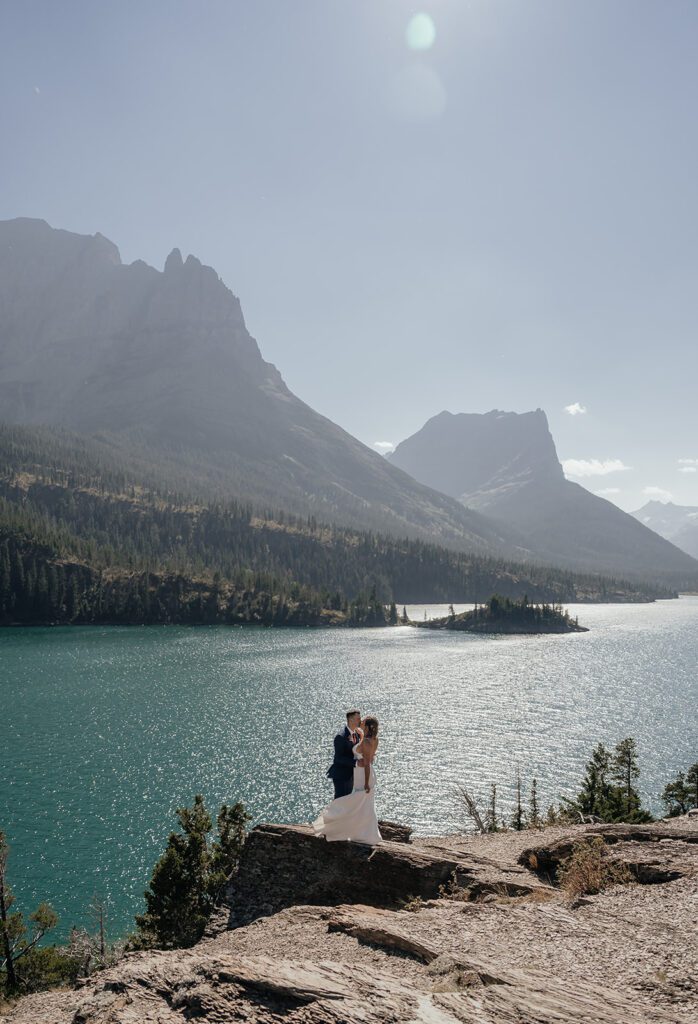 Clear skies and bright sunshine shine above a bride and groom at Sun Point during a Glacier National Park destination wedding.