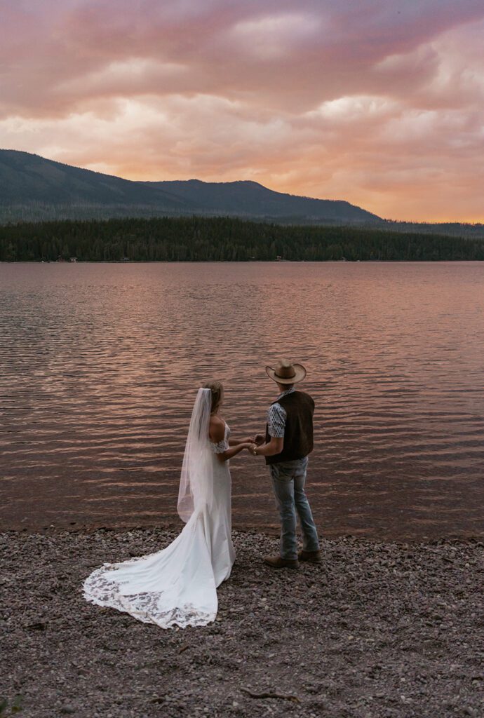 Bride and groom marvel in a gorgeous sunset at Lake McDonald.