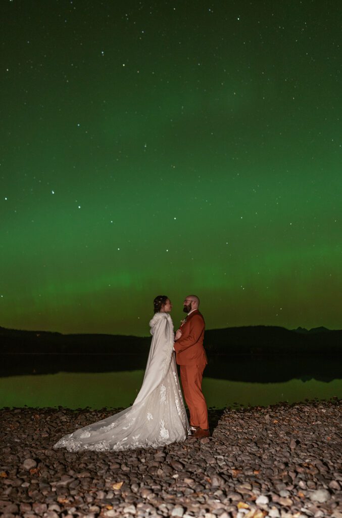 Newlyweds slow dance beneath the Northern Lights at Lake McDonald in Glacier National Park.
