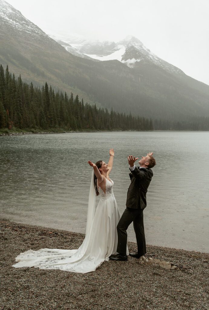 Newlyweds worship at Lake Josephine following their rainy elopement in Glacier National Park.