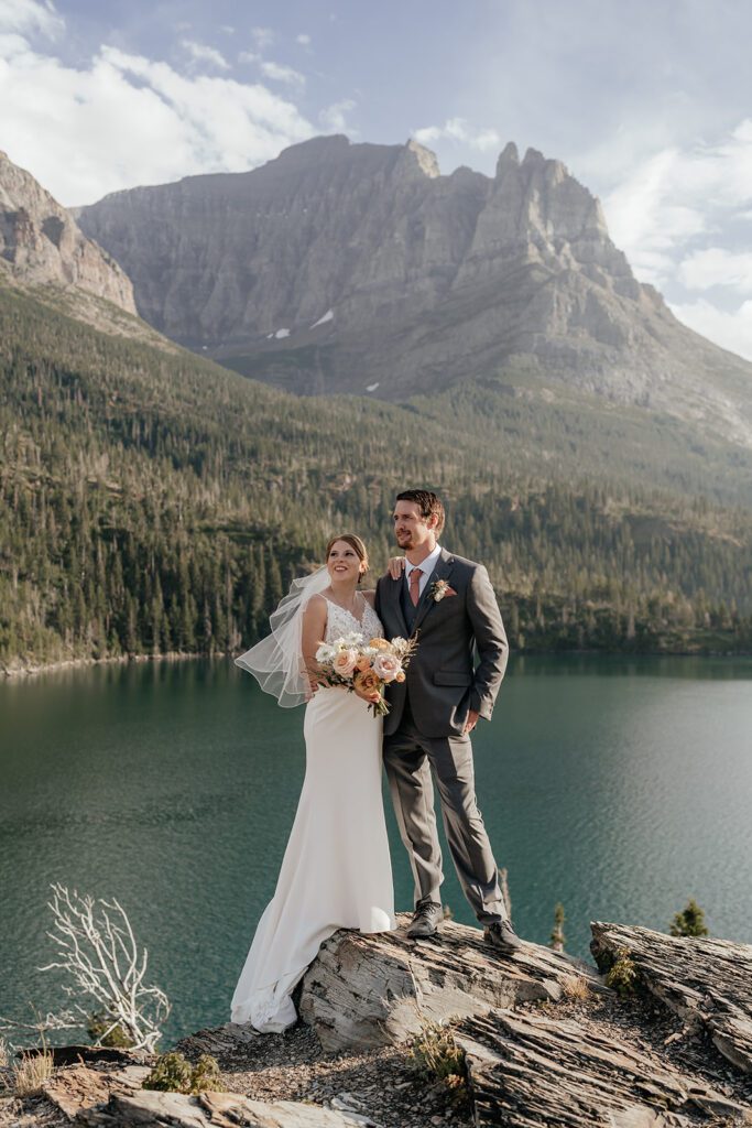 Bride and groom stare off into the distance at Sun Point while St. Mary Lake gently ripples below.