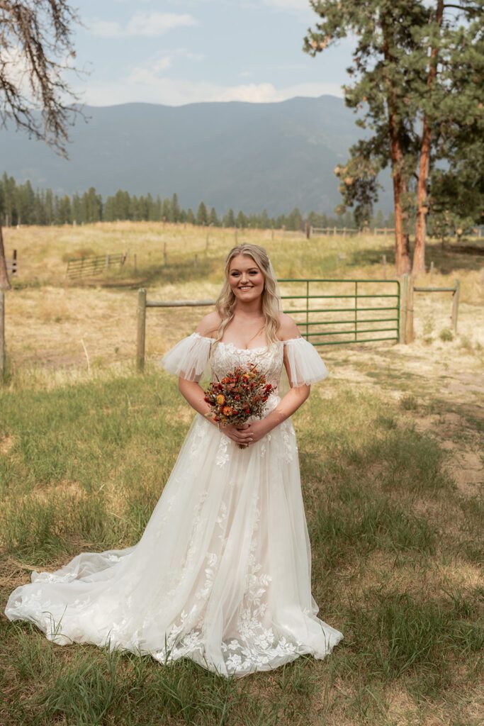 Western-chic bride wearing a whimsical off the shoulder a-line gown with tulle flutter sleeves during a Northwest Montana intimate wedding at an Airbnb near Glacier National Park