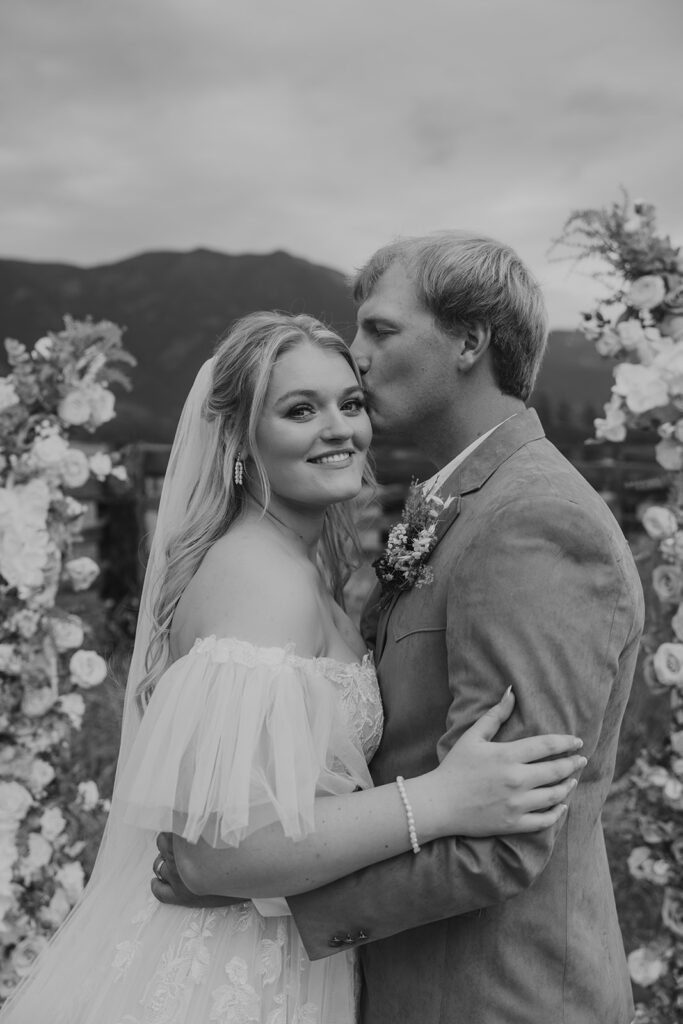 Western-chic bride wearing a whimsical off the shoulder a-line gown with tulle flutter sleeves during a Northwest Montana intimate wedding at an Airbnb near Glacier National Park