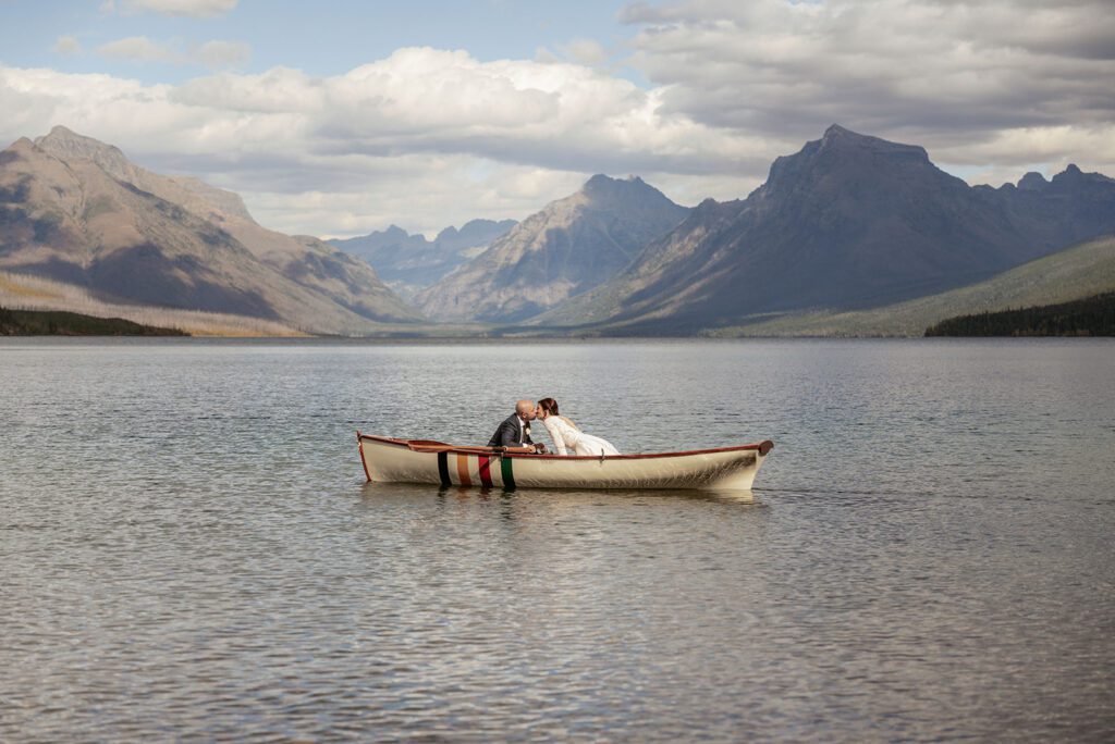An adventurous elopement couple canoes on Lake McDonald following their intimate wedding ceremony on Ryan Beach in Glacier National Park