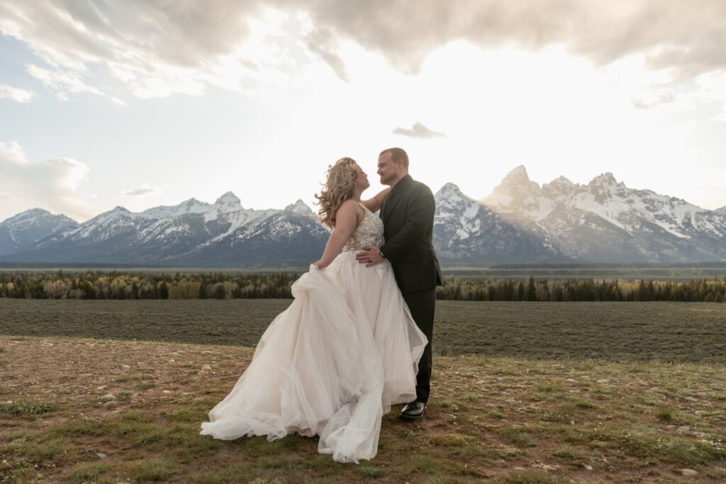 Newlyweds frolic along Mormon Row in Grand Teton National Park following their romantic mountain elopement, photographed by Sydney Breann Photography.