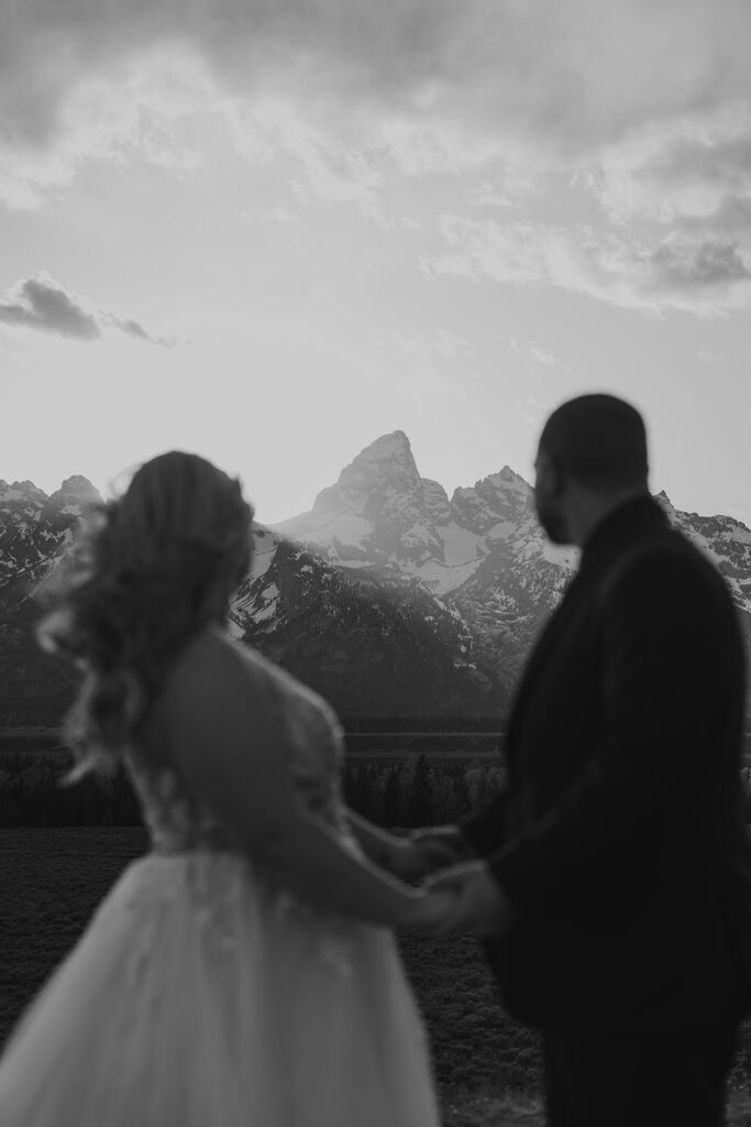 Newlyweds frolic along Mormon Row in Grand Teton National Park following their romantic mountain elopement, photographed by Sydney Breann Photography.