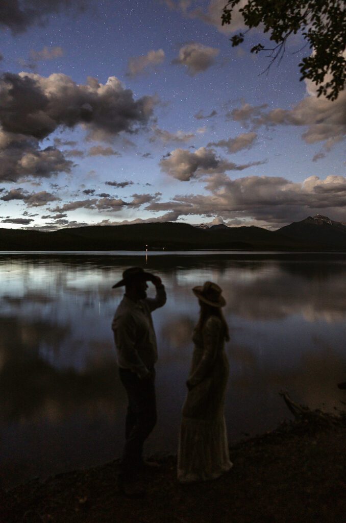 Newlyweds stargaze over a lake in Glacier National Park at twilight