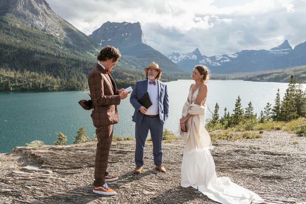 A groom reads his heartfelt vows to his bride during an intimate wedding ceremony at Sun Point in Glacier National Park.