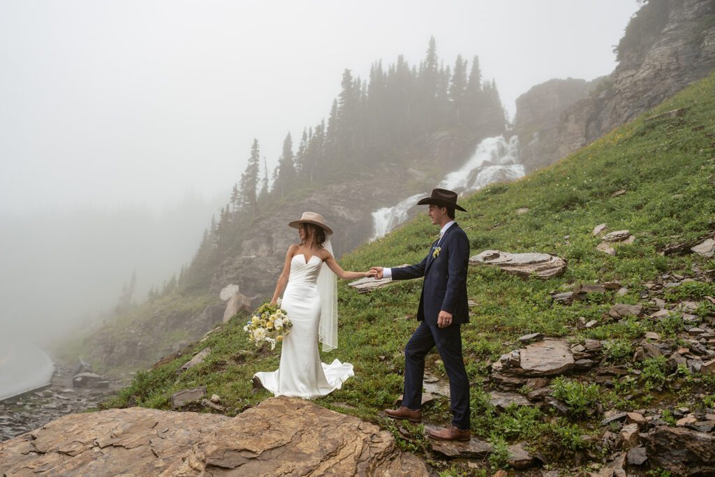 Moody bridal portraits as fog drifts across the valley below in Glacier National Park during a magical mountain elopement photographed by Sydney Breann Photography.