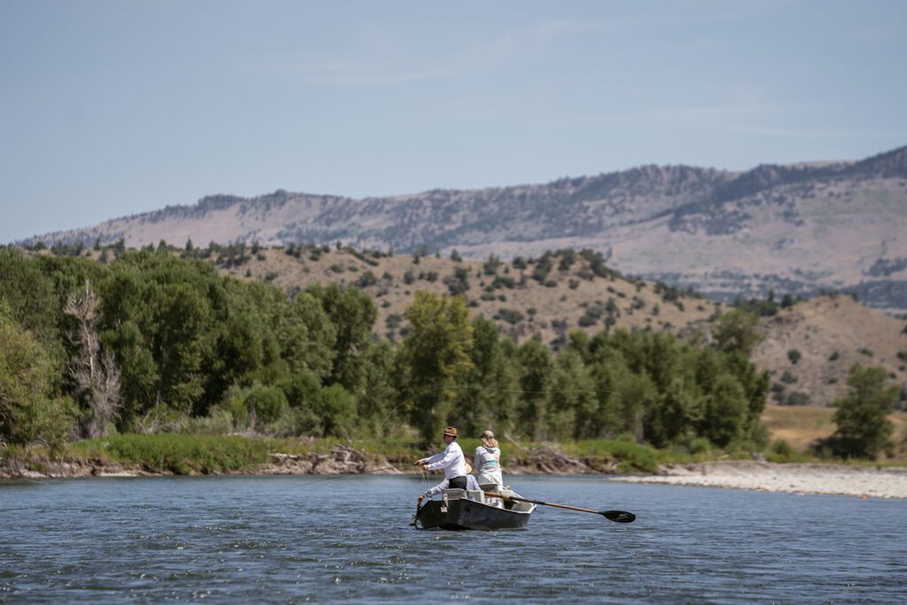 Newlyweds fly fish on the Yellowstone River during their adventurous Montana elopement photographed by Sydney Breann Photography.