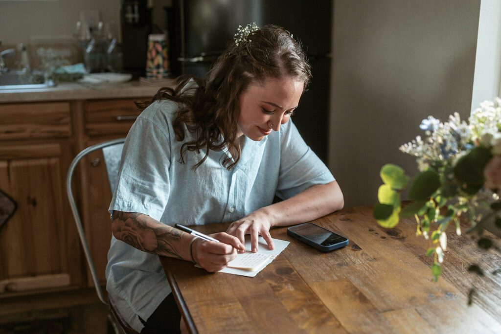 A bride copies her vows into a vow book during her wedding morning