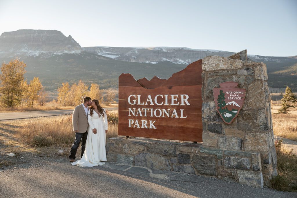 Bride and groom kiss at the Glacier National Park entrance sign
